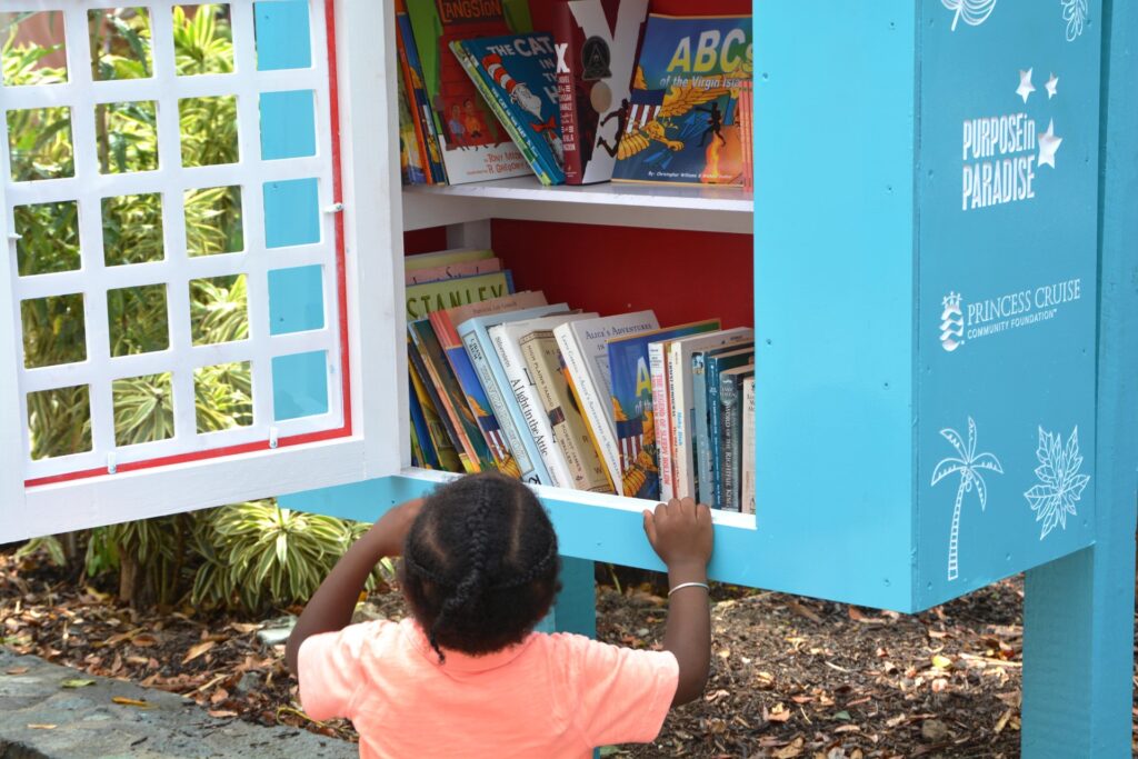 A small child reading through book titles in Little Free Libraries book depository.