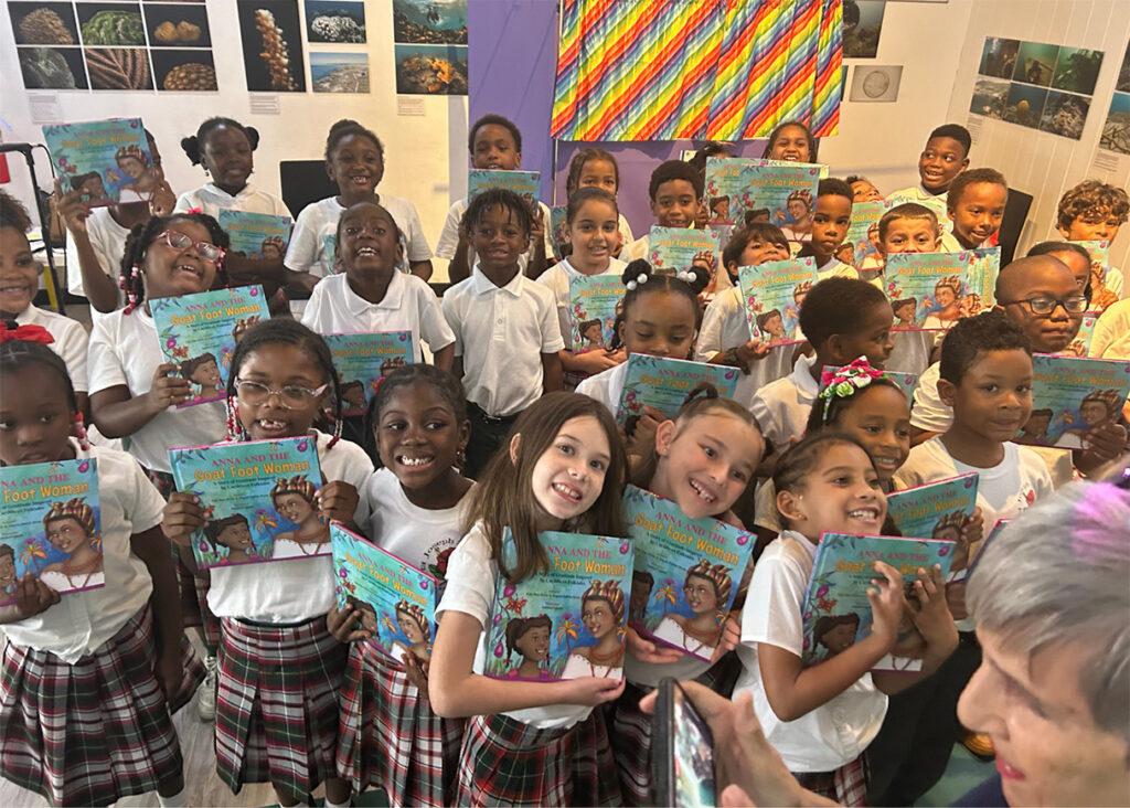 A classroom full of children holding Anna and the Goat Foot Woman: A Story of Gratitude Inspired by Caribbean Folktales